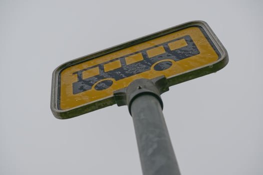 Weathered Bus Stop Sign Against Gray Sky photo