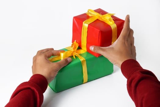 Two hands in red sweaters holding several green and red gifts box photo