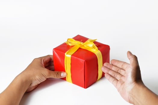 A Hand Presenting a Red Gift Box with a Golden Ribbon photo