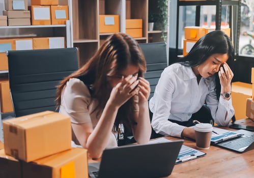 Two women sitting at a table with boxes on the desk photo