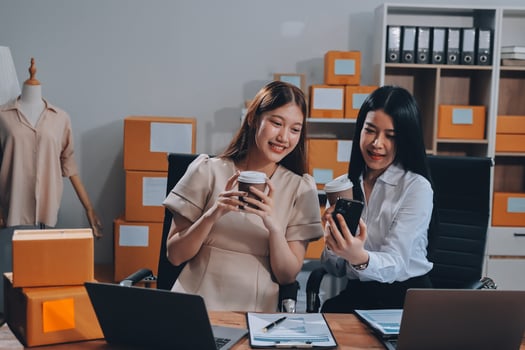 Two women in an office looking at their phones photo