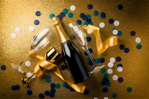 Champagne bottle uncorked beside glasses, golden background celebrating New Years Eve photo