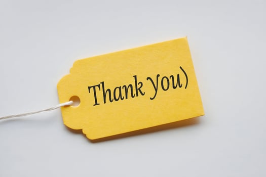 Yellow THANK YOU tag against white background conveys appreciation and elegance photo