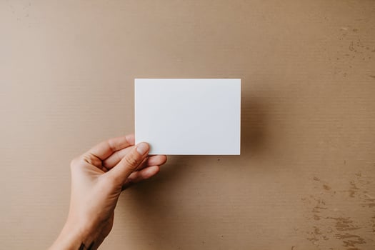 Hand holds a blank white card against a textured cardboard surface, focusing on versatility photo