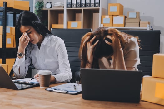 Two women sitting at a desk with laptops photo