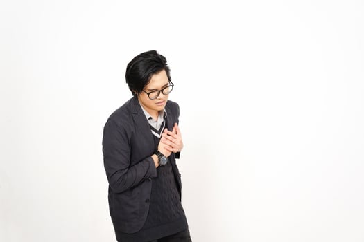 A man in glasses and a suit standing in front of a white wall photo