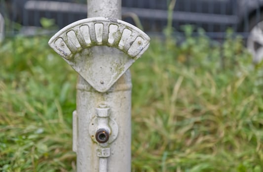 Weathered Metal Pole with Gauge in Grass photo