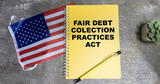 Concept of Fair Debt Collection Practices Act write on book and Flag of the United States isolated on Wooden Table. photo
