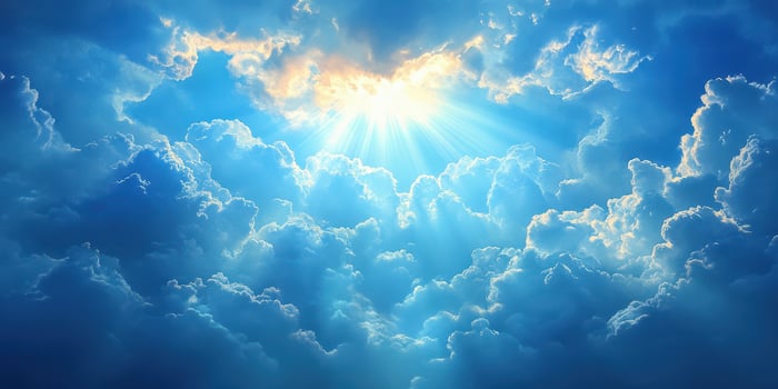 Bright sunlight breaking through fluffy clouds in a clear blue sky at midday photo