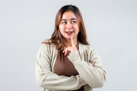 A playful young woman poses with a finger on her lips, suggesting secrecy. Her casual attire and expressive demeanor make this image ideal for lifestyle, social media, and creative projects. photo