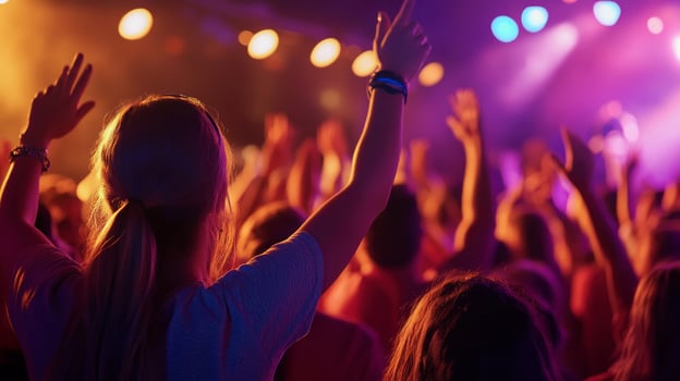 A crowd of people at a concert with their hands up photo