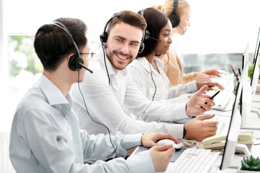 Happy male technical support operators having friendly chat at call centre. Positive millennial hotline consultants communicating at workplace. Helpline service concept photo