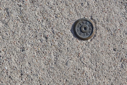Close-up of Metal Park Marker on Concrete photo