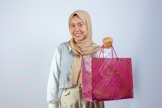 Happy Muslim Woman Holding Shopping Bag with Joyful Expression photo