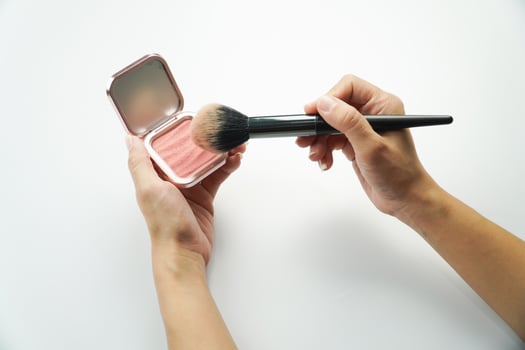 A woman holding a brush and a blush compact photo