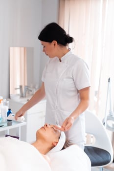 Dermatologist preparing female client for massage at salon photo