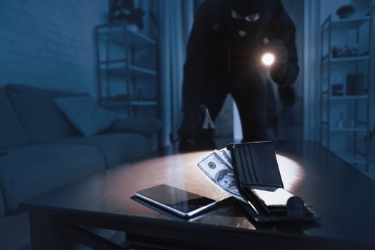Home Invasion. Masked robber breaking into home at night through back door, using flashlight on cash and smart phone photo