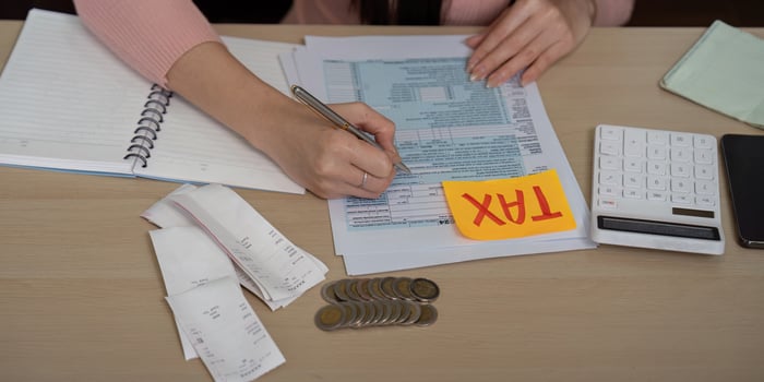 Detailed view of woman filling out tax forms with coins and calculator photo