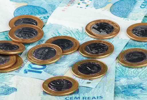Brazilian money. Close-up of Brazilian currency, featuring 1 Real coins scattered on top of 100 Real banknotes photo