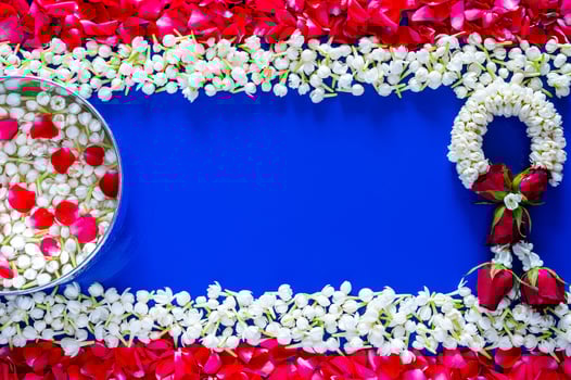 Flowers in water bowl for blessing with jasmine garland on blue background set as Thailand flag with jasmine and red rose petal for Thailand Songkran festival background. photo