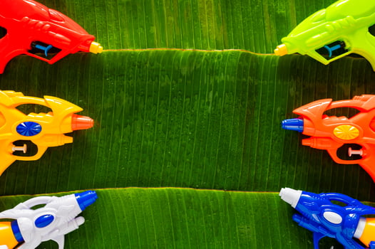 Water guns put on wet banana leaves background for Minimal Thailand Songkran festival celebration concept. photo
