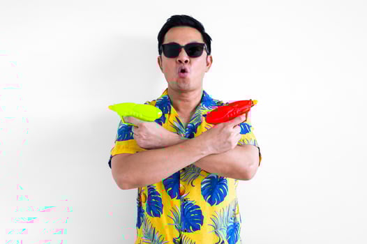 Thai male get excited while holding blurred focus of water guns wearing colorful shirt for Thailand Songkran festival concept. photo