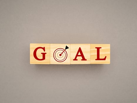 Wooden cubes with the letters GOAL and dartboard on a gray background photo