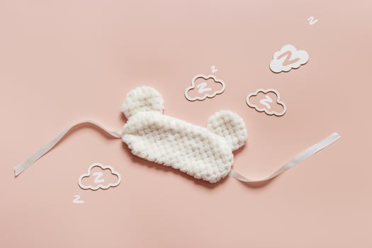 Sleep mask from soft nice fur and clouds shape with zz snore sounds on pink background. Light Fluffy eye cover mask for best sleep. Concept of travel comfort, dream well, rest at night, Minimal photo