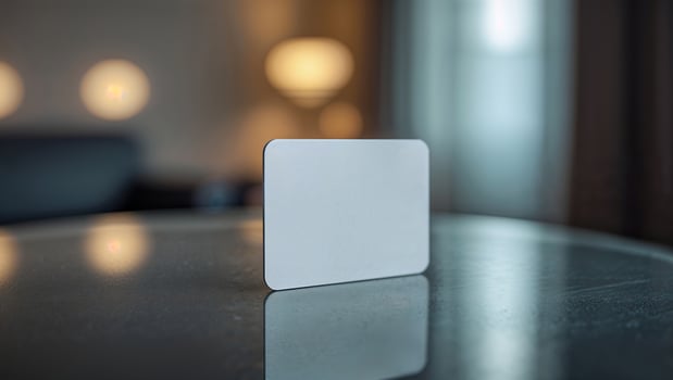 Blank card placed on a reflective table in a softly lit indoor space during evening hours photo