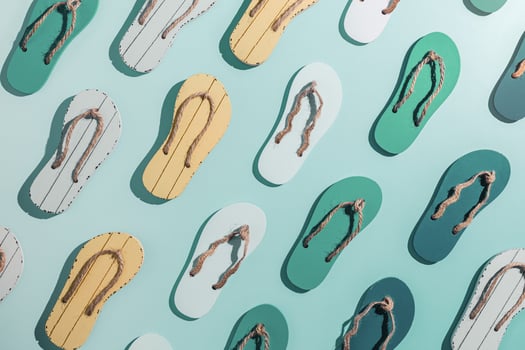 Female summer shoes sandals as creative minimal pattern with hard shadow, blue green yellow flip flops on turquoise gradient color background. Aesthetic trend summer fashion concept, life style photo