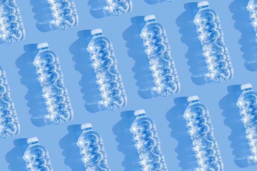 Minimal Pattern Plastic bottles water at sunlight, shadow on blue, aesthetic top view. Distilled drinking water. Pollution, environmental protection. Eco trend to reduce disposable plastics photo
