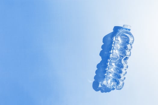 Plastic bottle water at sunlight with shadow, sun glare on blue background, aesthetic top view. Distilled drinking water. Pollution, environmental protection. reduce disposable plastics photo