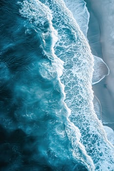 Aerial view of waves crashing onto a sandy beach with turquoise ocean water photo