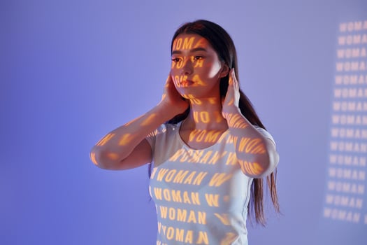 A woman with her hands on her ears and a word written on her face photo