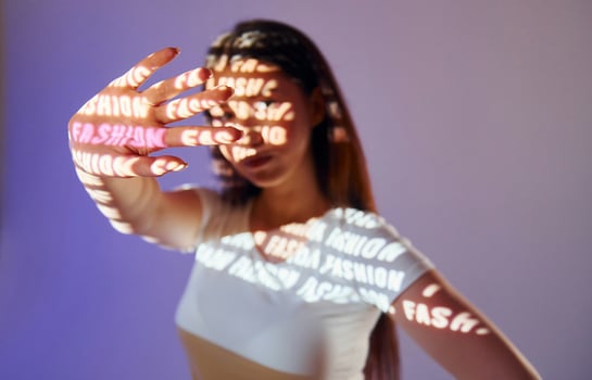 A woman holding up a hand with words projected on it photo