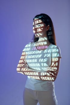 A woman standing in front of a wall with a lighted up text photo