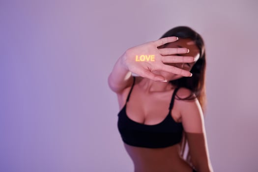 A woman in a black top and bra top holding up a sign that says love photo