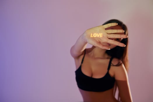 A woman in a black bra top holding up a sign that says love photo
