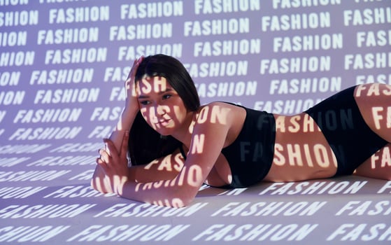 A woman laying on a bed with the words fashion on the wall photo
