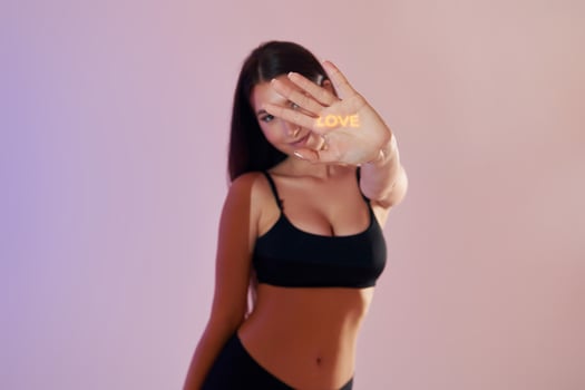 A woman in a sports bra top is holding up her hand photo