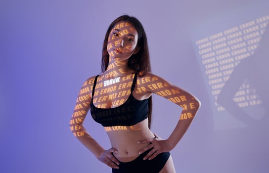 A woman in a black bra top and underwear standing in front of a wall with words on it photo
