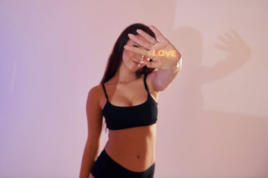 A woman in a black bra top holding up a sign that says love photo