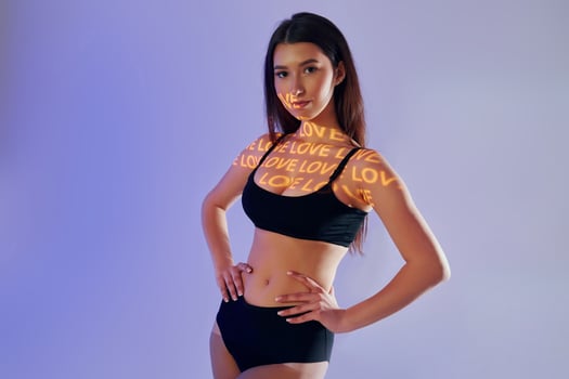 A woman in a black top and shorts posing with the words love on her chest photo