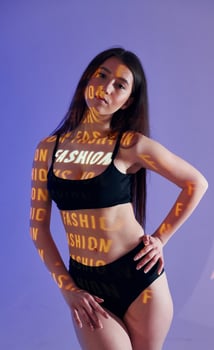 A woman in a bikini top and underwear posing in front of a blue background photo