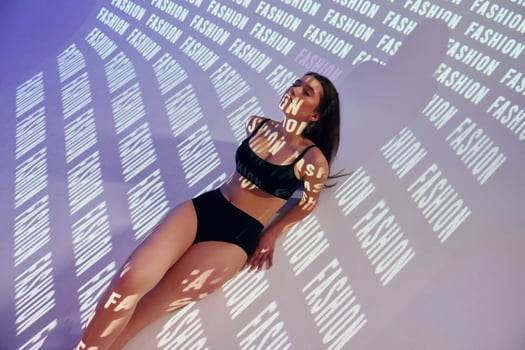A woman in a black bikini top and underwear laying on a wall photo