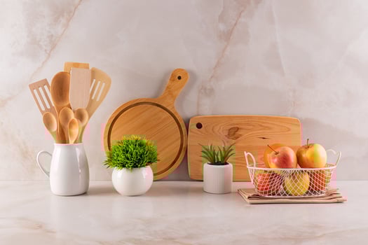 Beautiful still life on a beige marble countertop in the kitchen space. A set of kitchen tools, cutting boards and a bowl of fruit. potted plants. photo