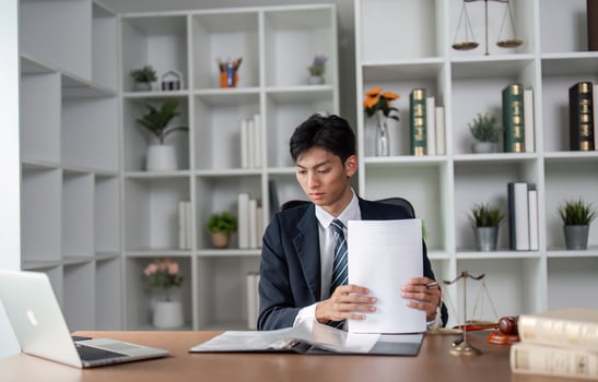 Young professional in suit examining documents at desk, focused on analysis and decision-making in modern office. photo