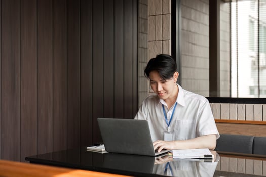Young professional typing on laptop in modern office, demonstrating focus and commitment to work tasks. photo