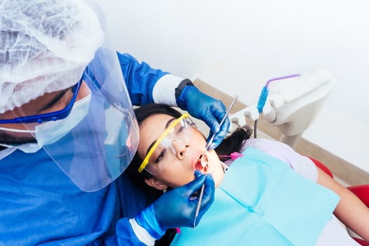 male dentist with bio safety suit attending and doing an oral examination to female patient. dental clinic, health and oral hygiene concept. photo