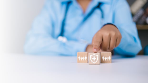 Human hands point to protection life insurance and investing to reduce risk, Doctor selects a wooden block with a symbol of protection and protection, Health care planning and insurance concept. photo